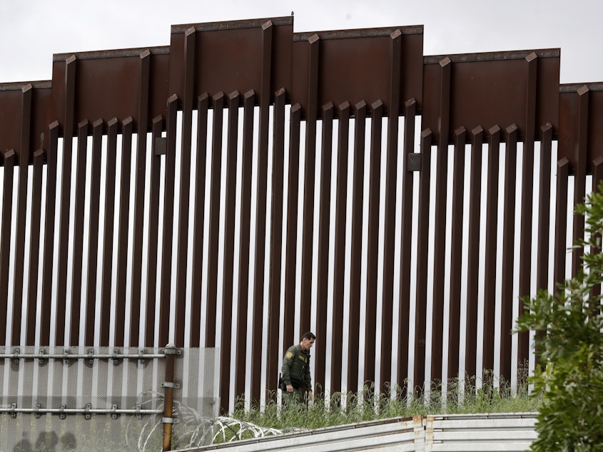 caption: A border patrol agent walked along a border wall separating Tijuana, Mexico, from San Diego earlier this week.