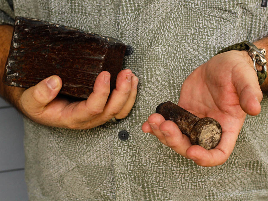 caption: Joe Dittmar holds remnants of the World Trade Center — a section from one of the core beams of the South Tower, right, and a bolt from a steel beam.