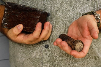 caption: Joe Dittmar holds remnants of the World Trade Center — a section from one of the core beams of the South Tower, right, and a bolt from a steel beam.