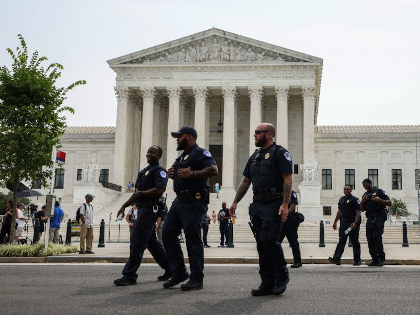 caption: U.S. Capitol police officers walk near the Capitol complex on July 19. Congress is voting to extend funding for the force.