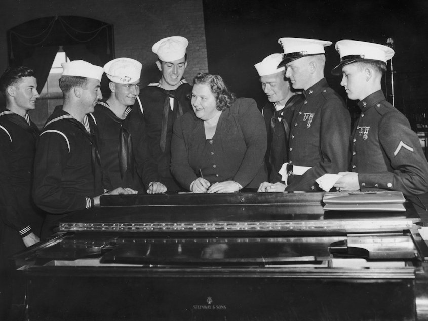 caption: Singer Kate Smith signs autographs for a group of American sailors circa 1938.