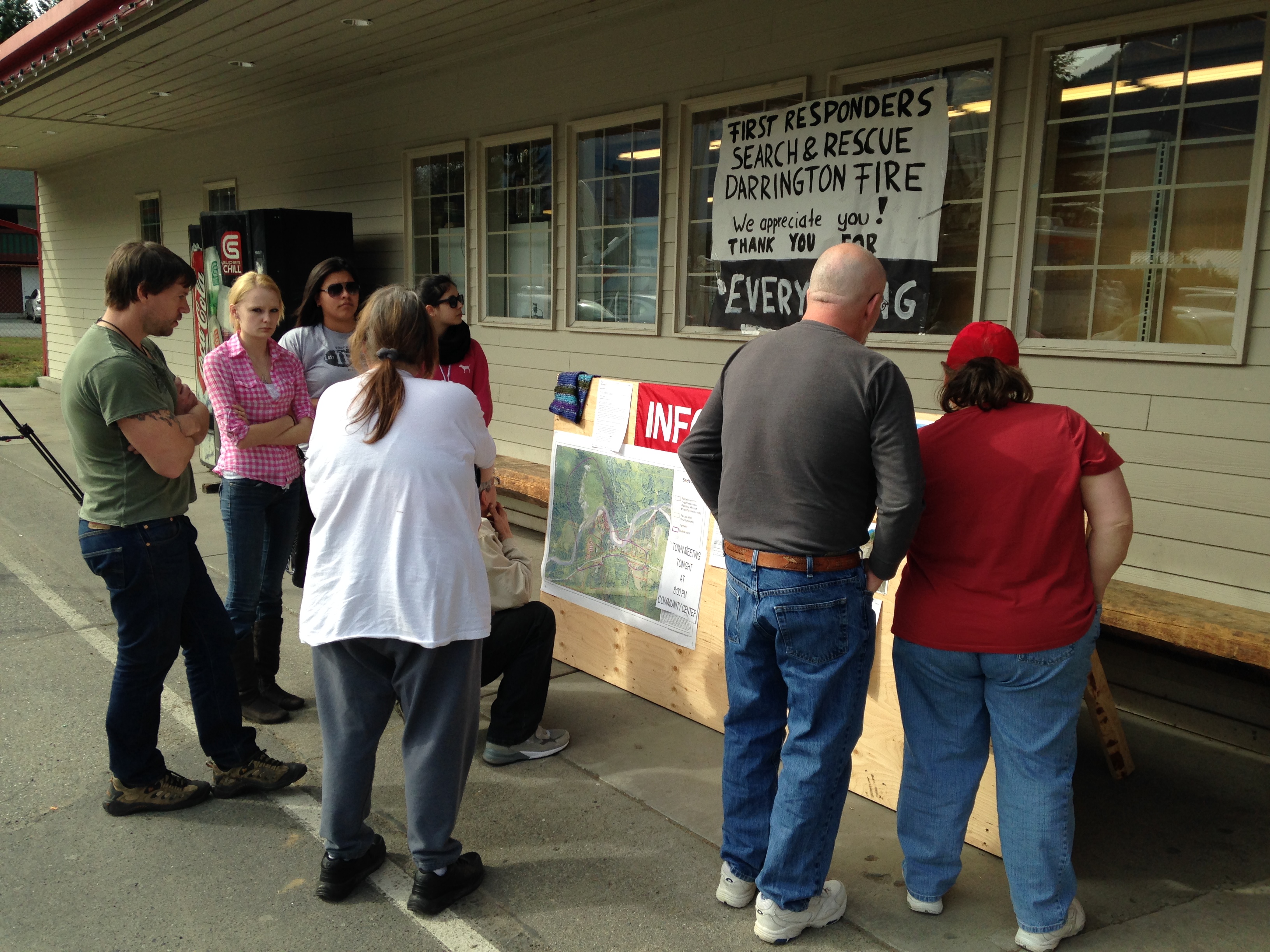 caption: Darrington residents gather outside town grocery store for word of missing.