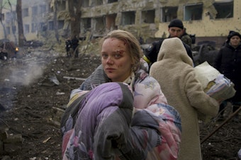 caption: Mariana Vishegirskaya stands outside a maternity hospital that was damaged by shelling in Mariupol, Ukraine, on March 9. Vishegirskaya later gave birth to a girl in another hospital in Mariupol.