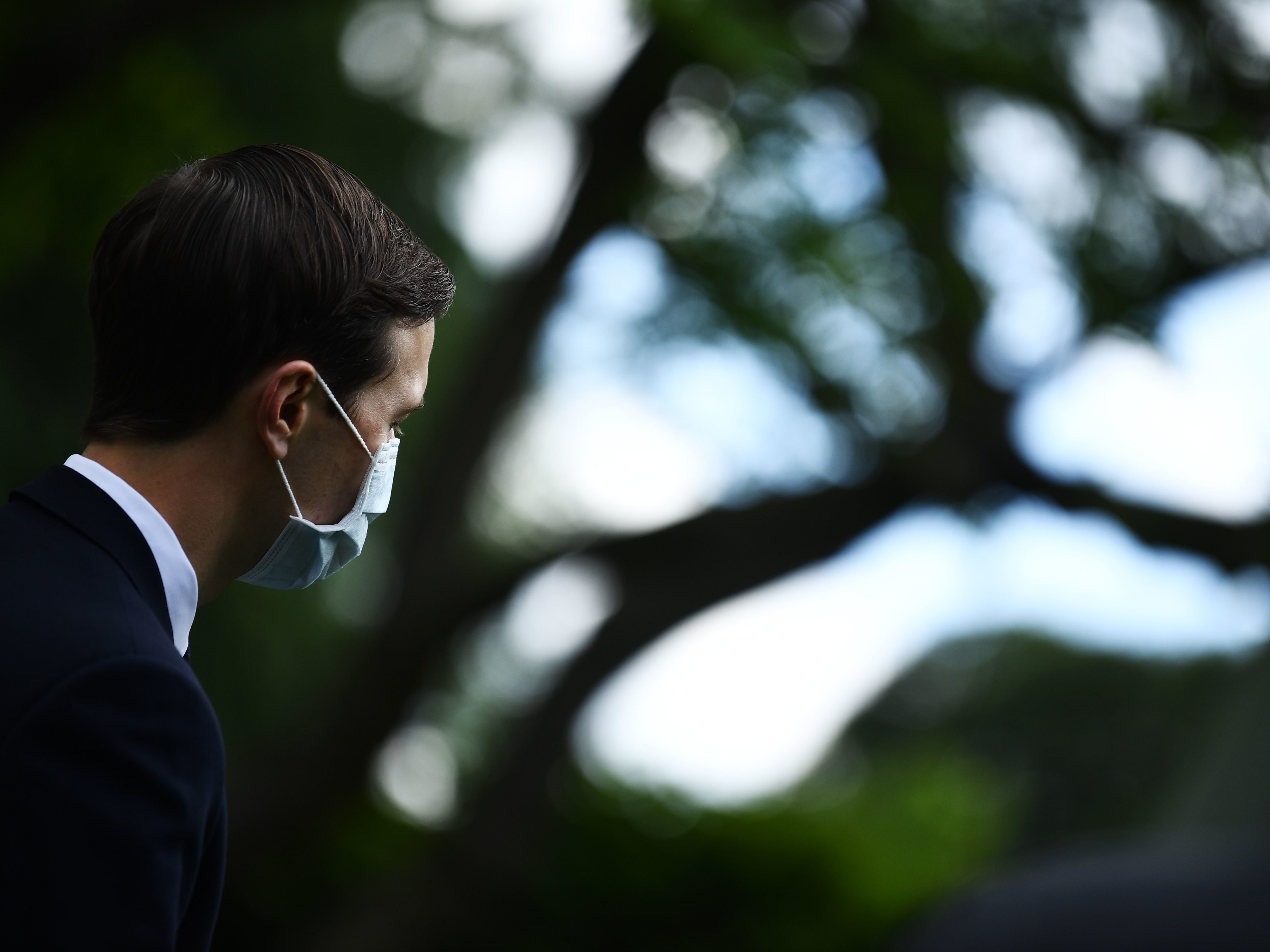 caption: Jared Kushner, President Trump's son-in-law and senior adviser, looks on while wearing a mask as Trump holds a news conference in the Rose Garden on Monday.