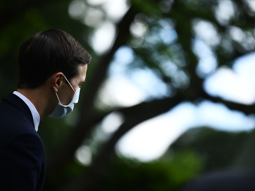 caption: Jared Kushner, President Trump's son-in-law and senior adviser, looks on while wearing a mask as Trump holds a news conference in the Rose Garden on Monday.