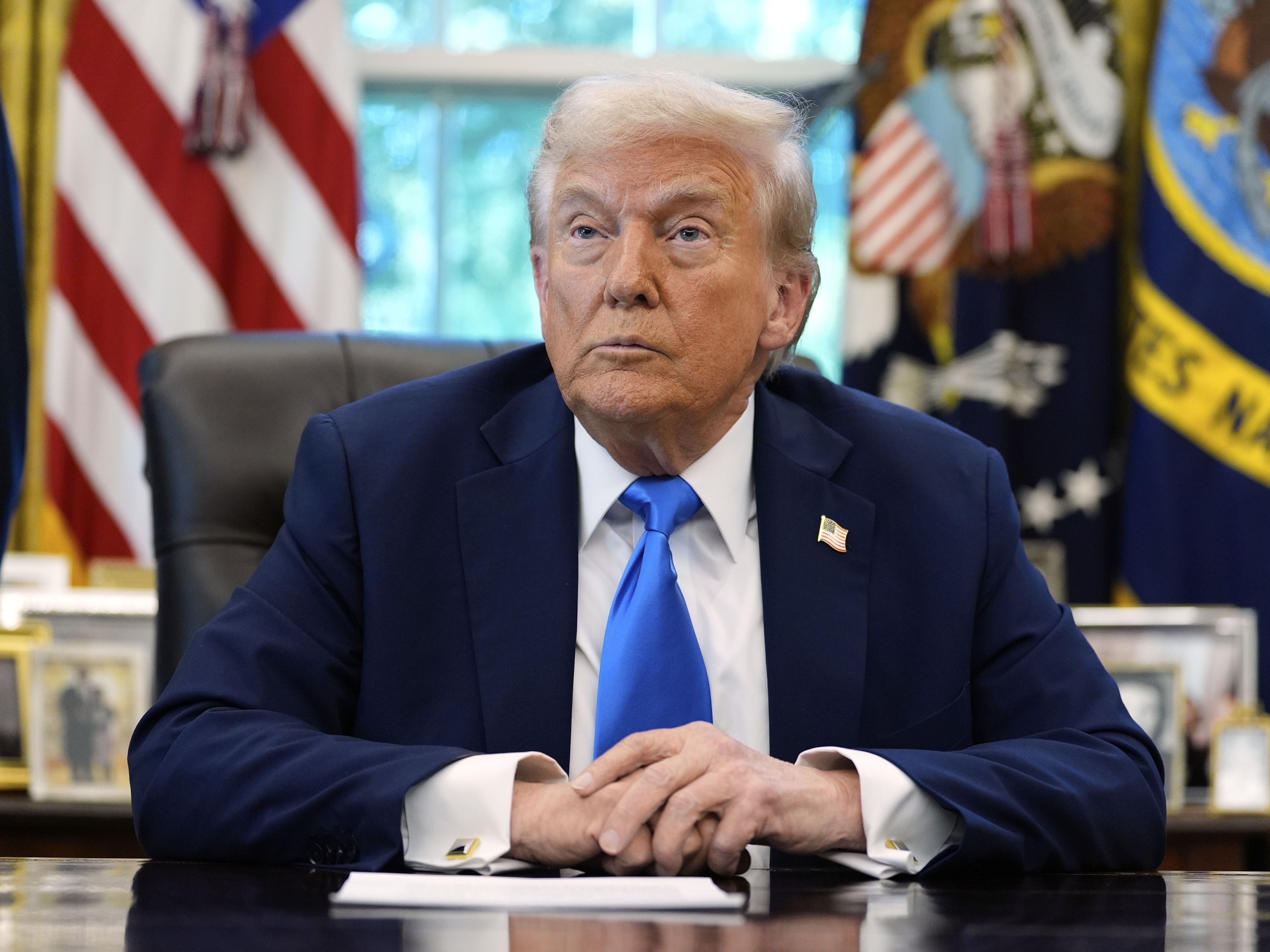 caption: President Donald Trump listens to a reporter's question in the Oval Office of the White House, on Friday.