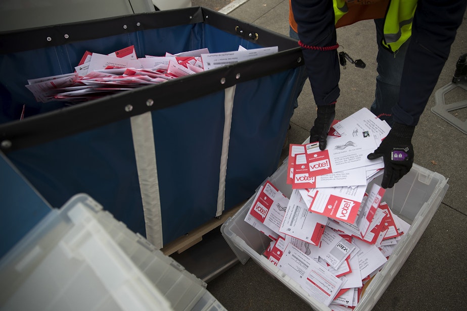 caption: FILE: King County Elections employee Josephine Ruff unloads a completely full ballot drop box outside of the Seattle Public Library on Tuesday, November 7, 2017, in Ballard. 