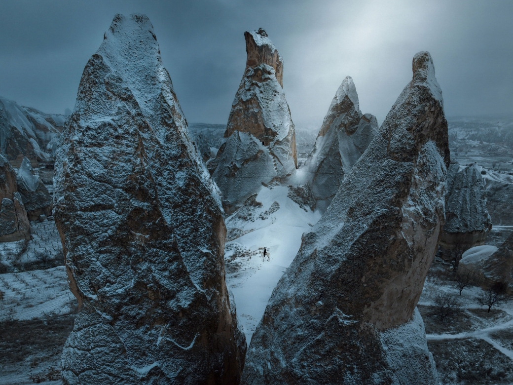 caption: A solitary horseman stands atop a rocky outcropping in Cappadocia, Turkey.