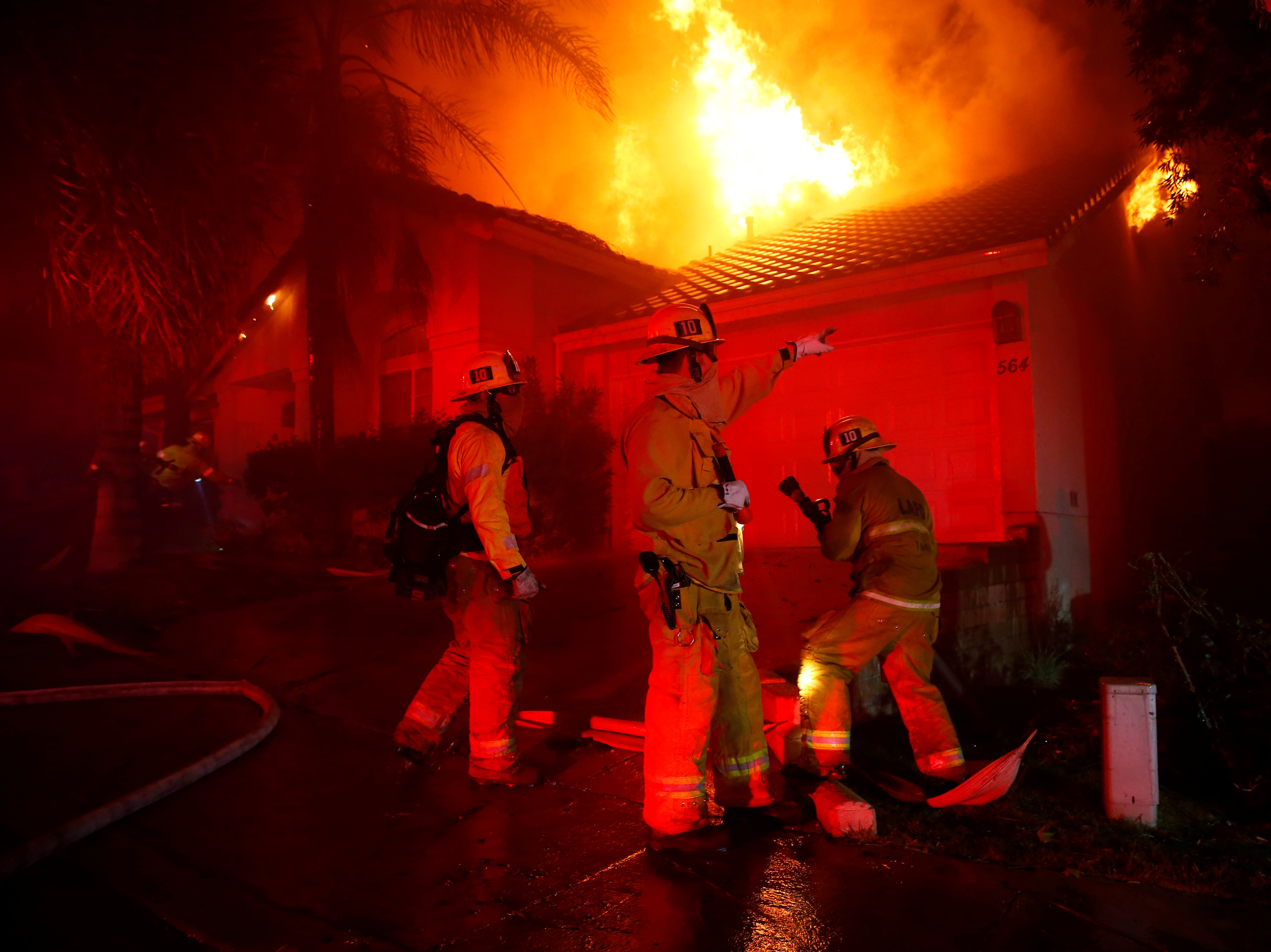 caption: Firefighters try to beat the Woolsey Fire in the early hours Friday. One day earlier, the blaze ignited as mourning residents tried to cope with quite another kind of terror in Thousand Oaks, Calif.