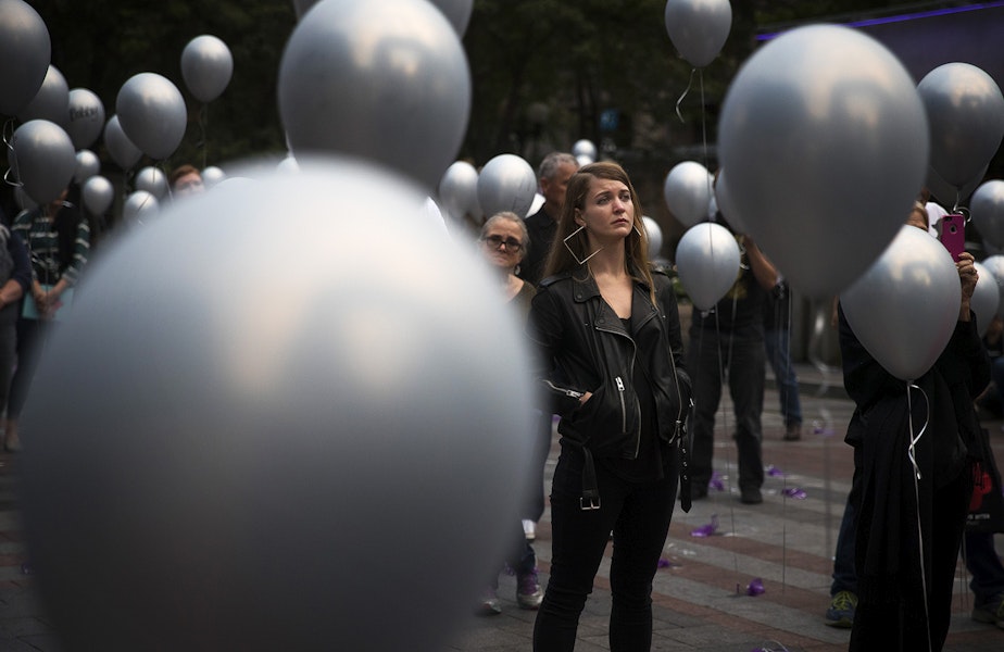 caption: Cassandra Piester, center, listens to speakers during an event honoring the 379 lives lost in King County during 2017 to overdose, on Thursday, August 30, 2018, at Westlake Park in Seattle. Piester's cousin Amber Roberts died of an overdose in 2015.