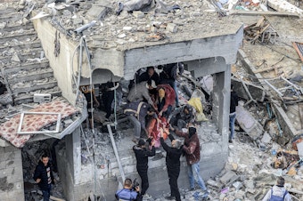 caption: Men recover the body of a Palestinian killed in the aftermath of an overnight Israeli strike at al-Maghazi refugee camp in Gaza on Monday, as the war between Israel and Hamas carries on.