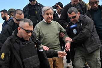 caption: U.N. Secretary-General Antonio Guterres walks with security personnel as his visits Borodyanka, a town outside Kyiv that was devastated by a Russian attack and occupation, on Thursday. Russia sent a deadly attack into the capital as Guterres visited.