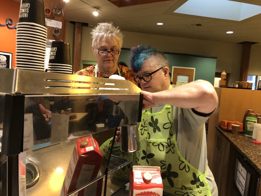 caption: Recovery Cafe members Joan Patrie, left, and k-bob make espresso drinks for fellow members. 