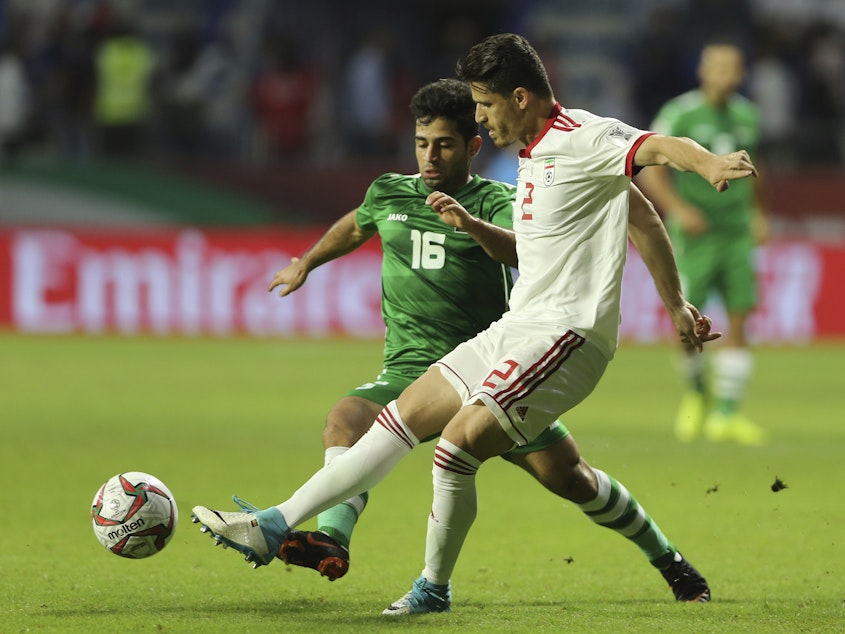 caption: Iranian soccer player Voria Ghafouri (right), then a member of the national soccer team, fights for the ball with Iraqi midfielder Hussein Ali during the AFC Asian Cup soccer match in Dubai in 2019. The semiofficial Fars and Tasnim news agencies reported on Thursday that Iran arrested Ghafouri for insulting the national soccer team and criticizing the government.