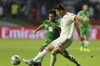 caption: Iranian soccer player Voria Ghafouri (right), then a member of the national soccer team, fights for the ball with Iraqi midfielder Hussein Ali during the AFC Asian Cup soccer match in Dubai in 2019. The semiofficial Fars and Tasnim news agencies reported on Thursday that Iran arrested Ghafouri for insulting the national soccer team and criticizing the government.