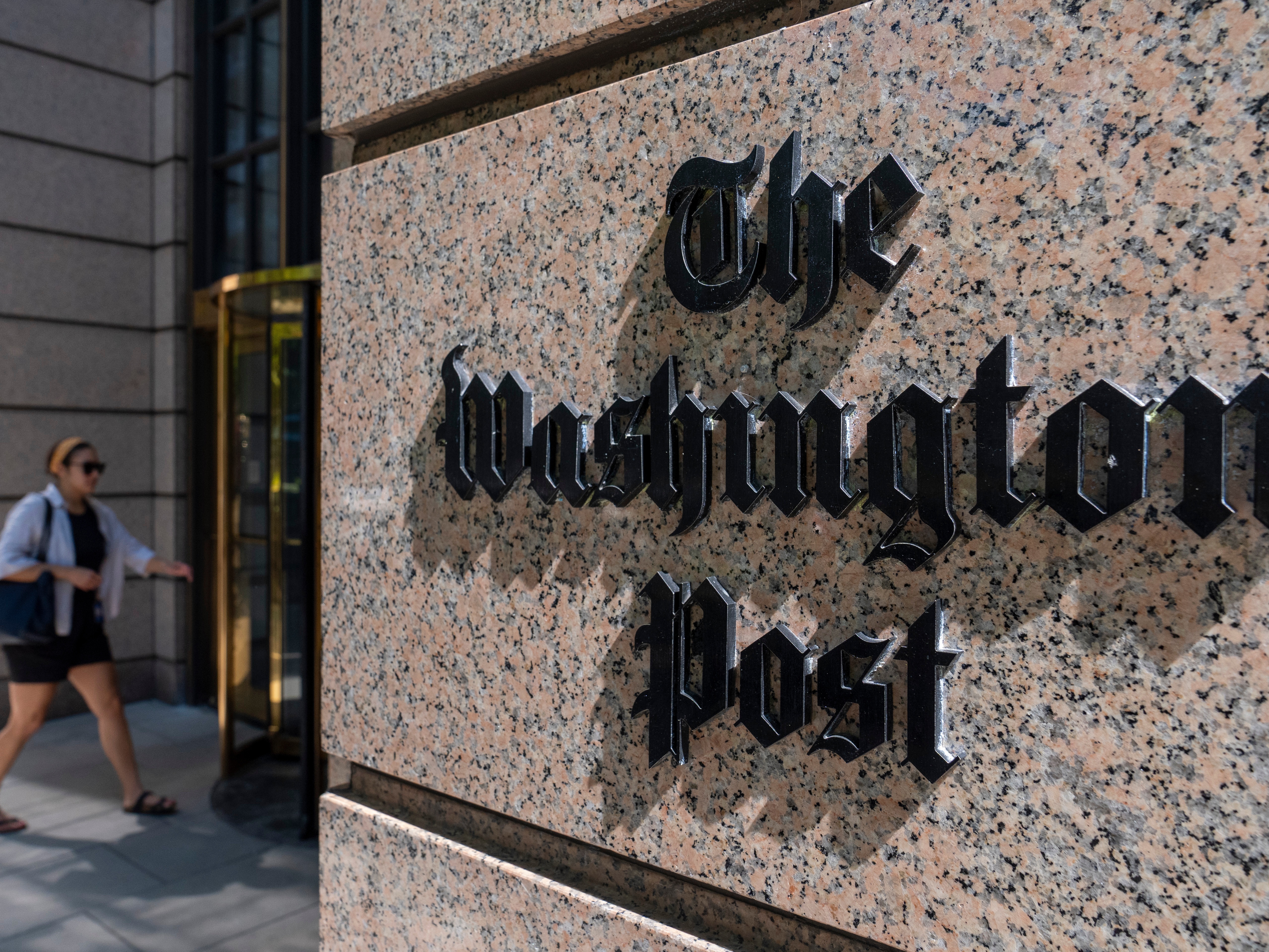 caption: A person walks into the One Franklin Square Building, home of The Washington Post newspaper, June 21, 2024, in Washington.