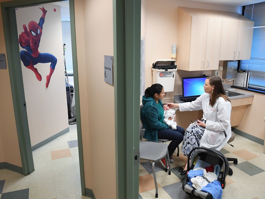 caption: Ana Elsy Ramirez Diaz holds her baby as he is seen by Dr. Margaret-Anne Fernandez during a checkup visit at INOVA Cares Clinic for Children in Falls Church, Va. A portion of the clinic's patients are insured through the Children's Health Insurance Program.