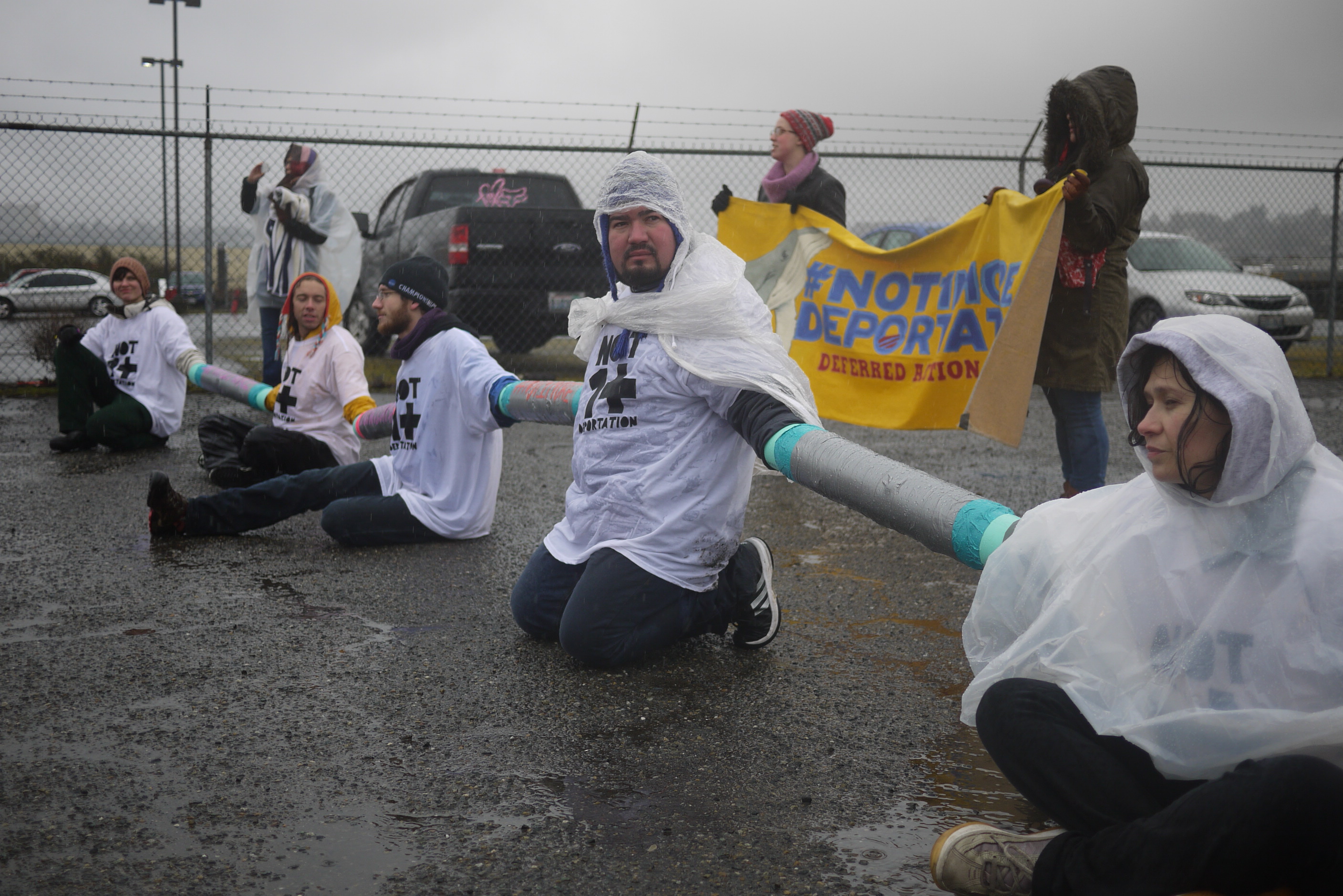caption: Protestors chain themselves outside the Northwest Detention Center to protest deportations.