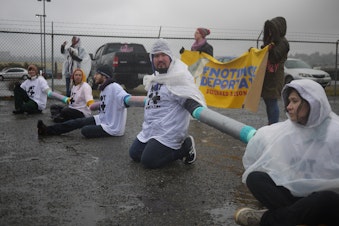 caption: Protestors chain themselves outside the Northwest Detention Center to protest deportations.