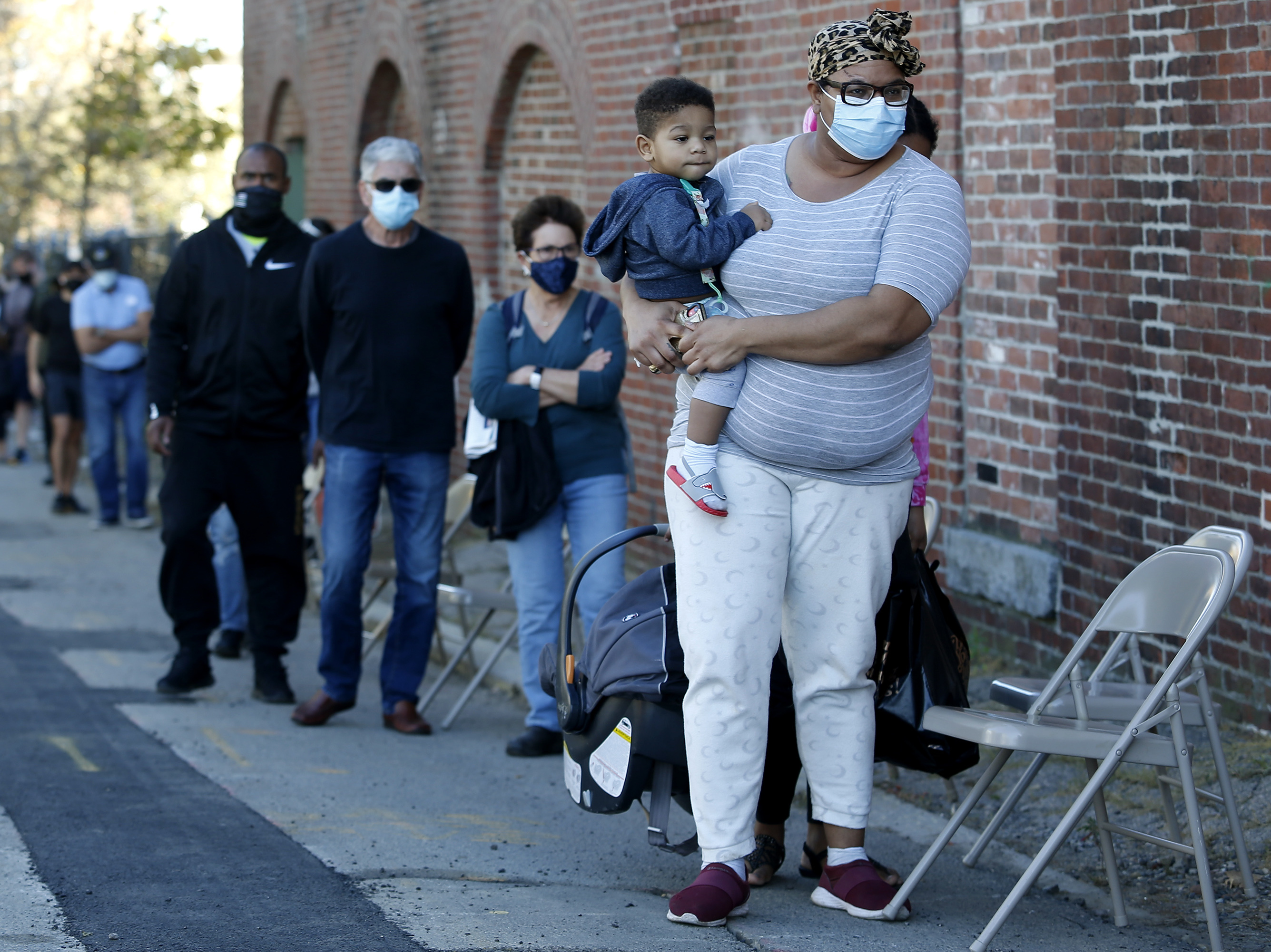caption: A woman holds her one year-old son as they wait in line to get a coronavirus test.