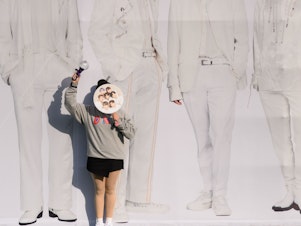 caption: A fan of K-pop band BTS poses for photos against a backdrop featuring an image of the group's members in Seoul, South Korea, on Oct. 29, 2019.