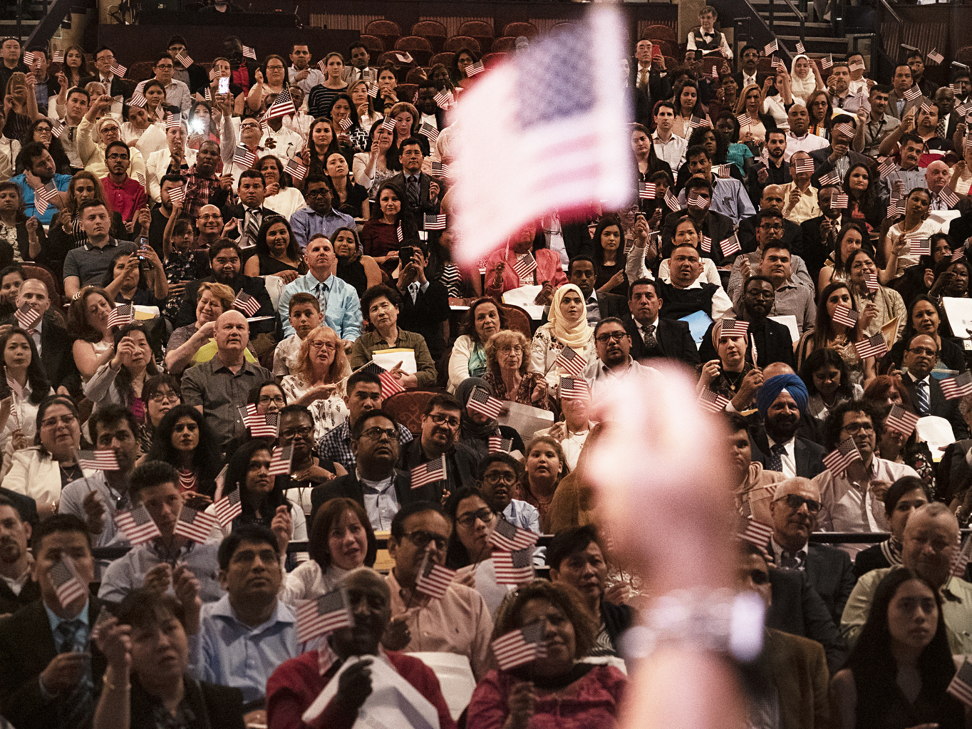 caption: A naturalization ceremony of new U.S. citizens at the Hylton Performing Arts Center in Manassas, Virginia. The U.S. citizenship oath today is 140 words. It wasn't until 1929 that the oath's text was standardized, and the oath was amended in 1952 to emphasize service to country as the U.S. faced a growing threat from the Soviet Union.