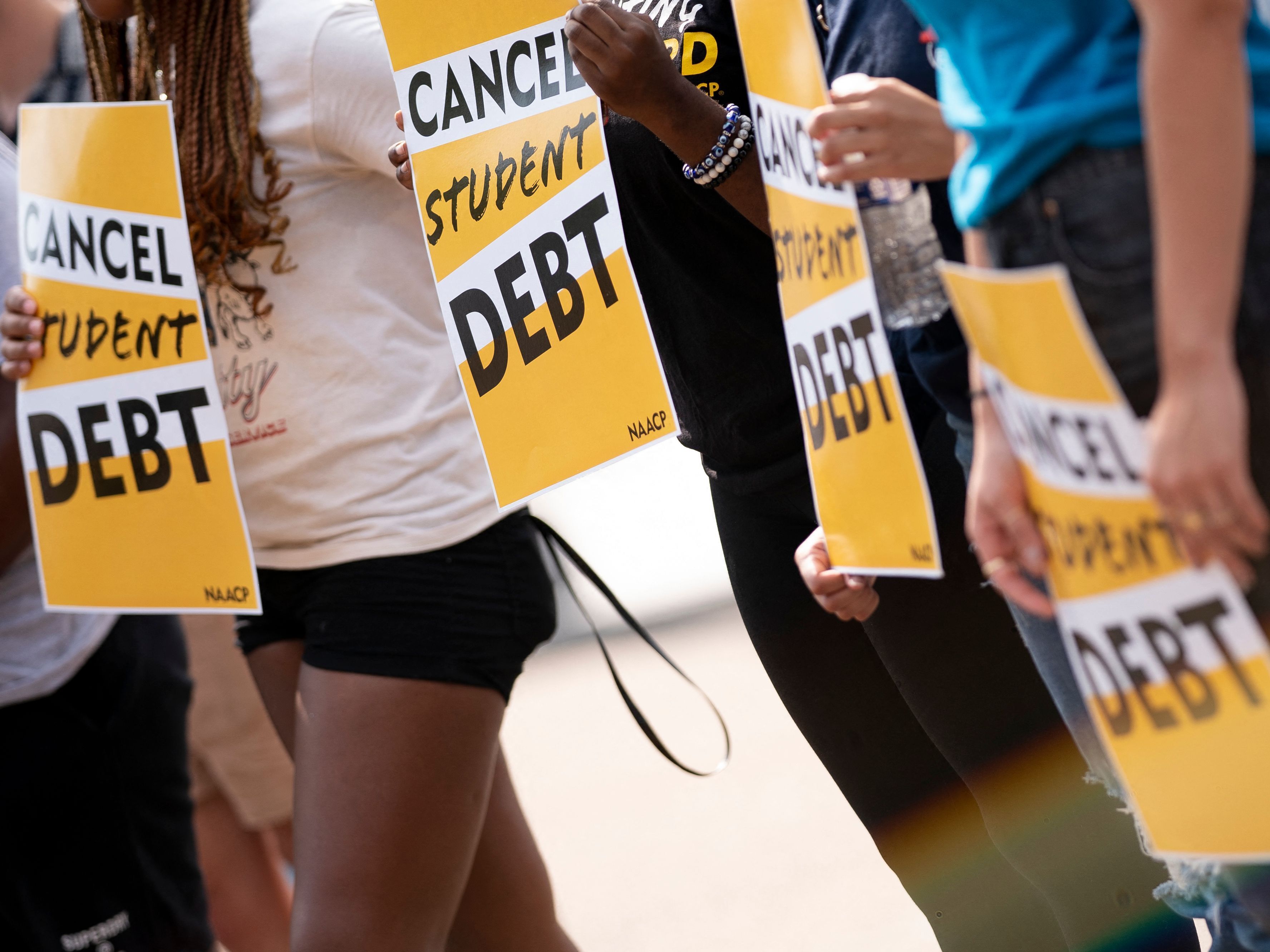 caption: Activists hold cancel student debt signs as they gather to rally in front of the White House in Washington, D.C., on Aug. 25.