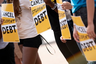caption: Activists hold cancel student debt signs as they gather to rally in front of the White House in Washington, D.C., on Aug. 25.
