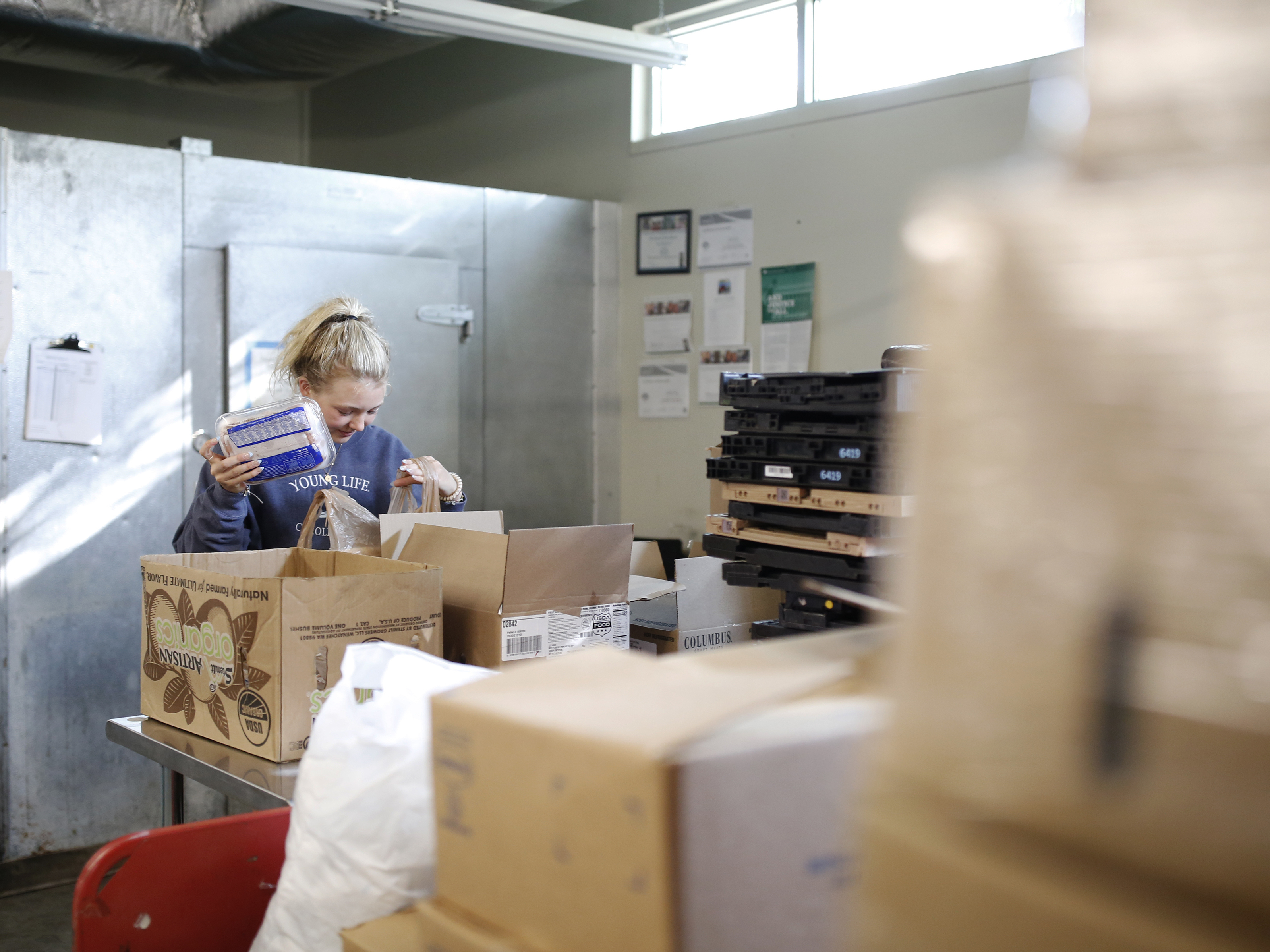 caption: Volunteer Ella Cagle of Wake Forest loads bags with frozen meat. The food bank serves individuals and families in need with a week's worth of groceries.