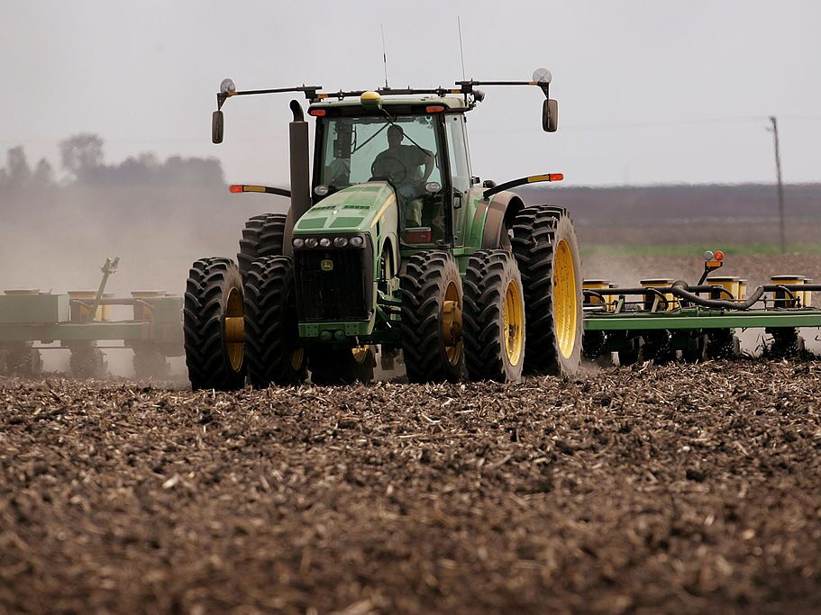 caption: A green tractor that's planting corn moves across a brown dirt field in 2007 near Rochelle, Ill.