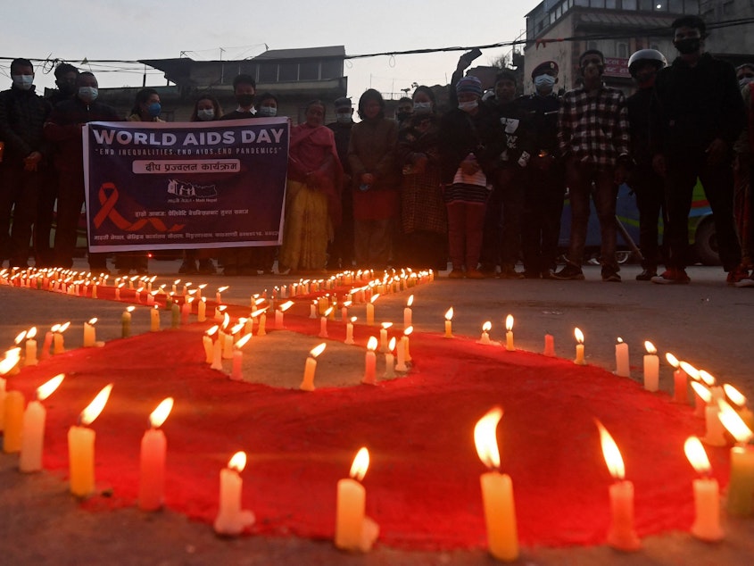 caption: Volunteers stand after lighting candles in the shape of a red ribbon during an awareness event ahead of World AIDS Day in Kathmandu on Tuesday.