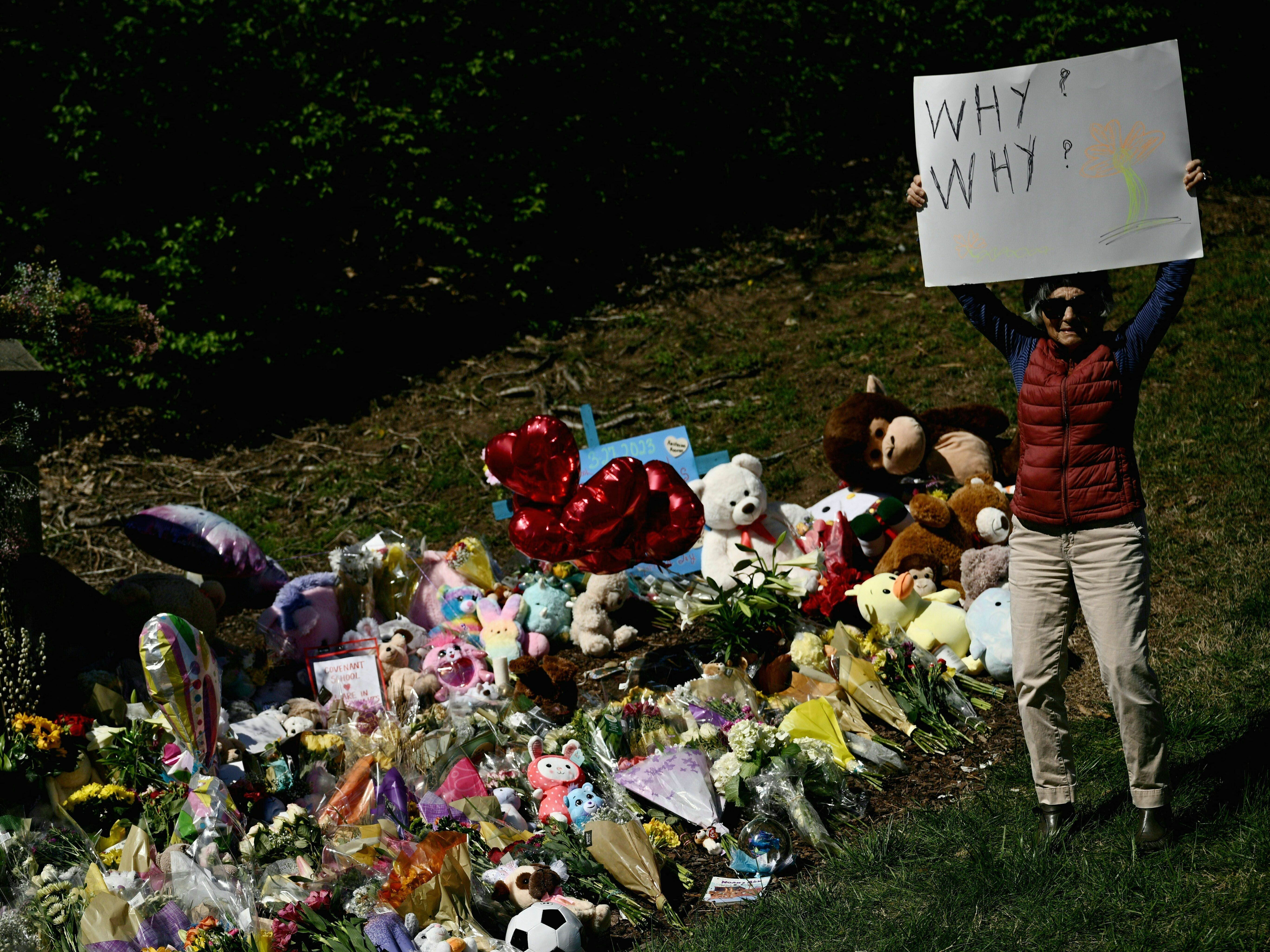 caption: A mourner holds a sign on Wednesday reading "Why? Why?" at a makeshift memorial for victims of a shooting at the Covenant School campus, in Nashville, Tenn.