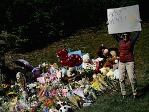 caption: A mourner holds a sign on Wednesday reading "Why? Why?" at a makeshift memorial for victims of a shooting at the Covenant School campus, in Nashville, Tenn.