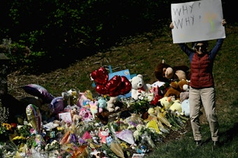 caption: A mourner holds a sign on Wednesday reading "Why? Why?" at a makeshift memorial for victims of a shooting at the Covenant School campus, in Nashville, Tenn.