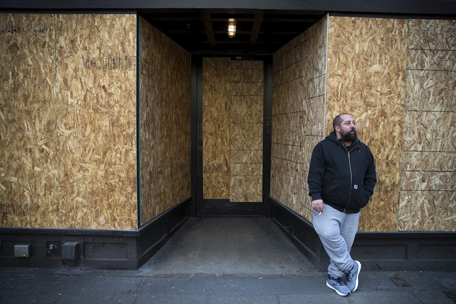 caption: Andy Aronis, Assistant General Manager of King's Hardware, smokes a cigarette outside of the boarded up bar and restaurant on Tuesday, March 17, 2020, on Ballard Avenue Northwest in Seattle. "I always felt good working in the bar industry because it's recession proof," said Aronis, who planned to file for unemployment. "The only thing you don't consider working in this industry is if there is a medical pandemic and then we are in the worst industry you could be in." 