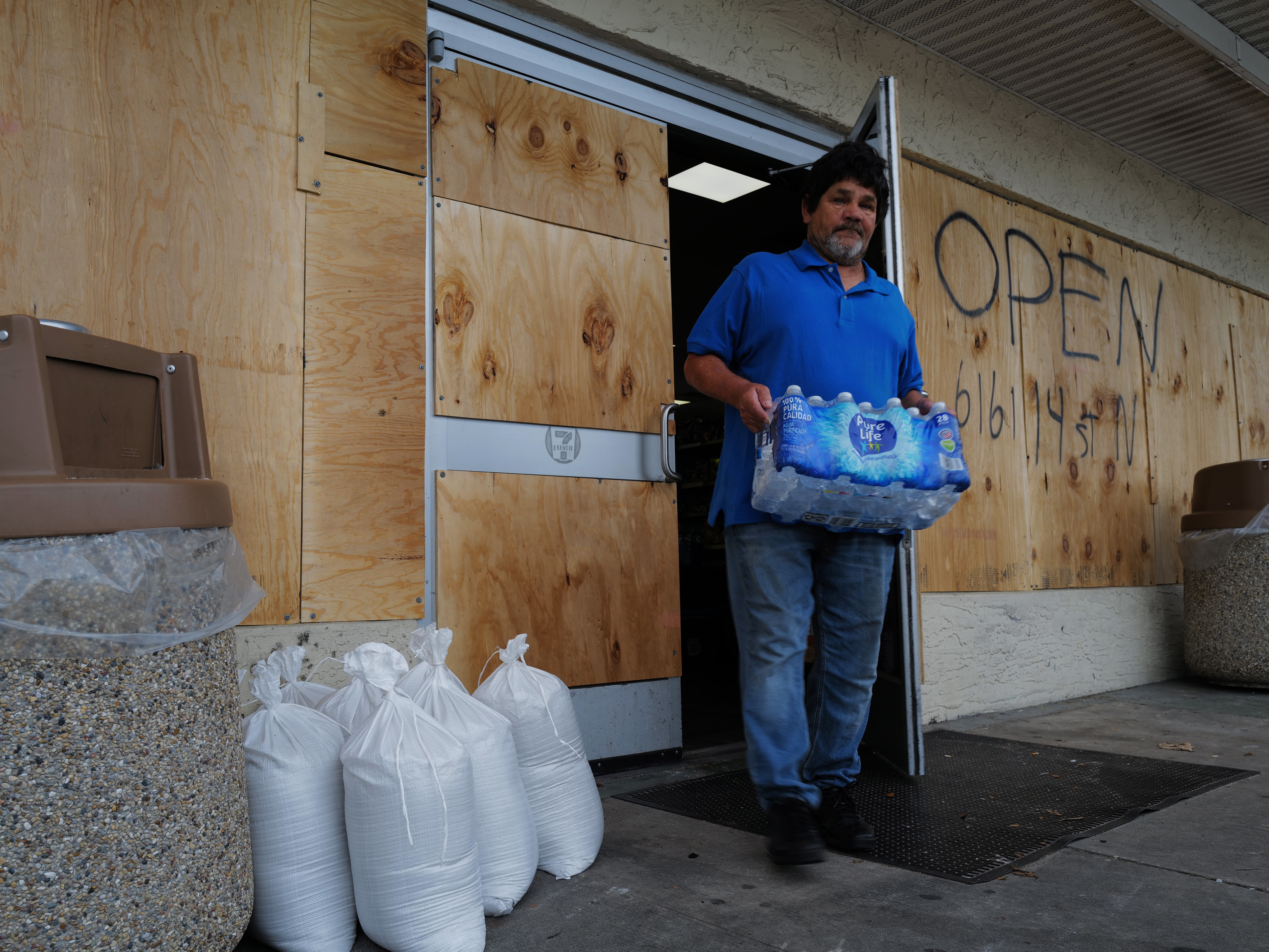 caption: People walk in and out of a boarded-up 7-Eleven on Tuesday in St. Petersburg, Fla., as the state prepares for the arrival of Hurricane Milton, which is expected to make landfall late Wednesday.