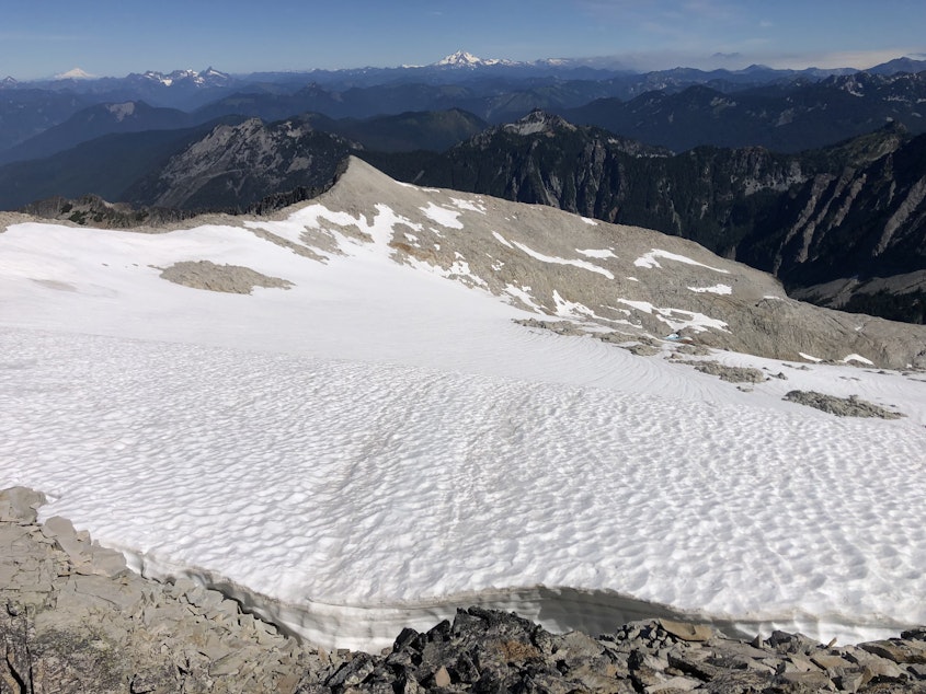 caption: The Foss Glacier, Mount Hinman’s sole remaining glacier, with Mount Baker, Glacier Peak, and wildfire smoke on the horizon on Aug. 14, 2022.
