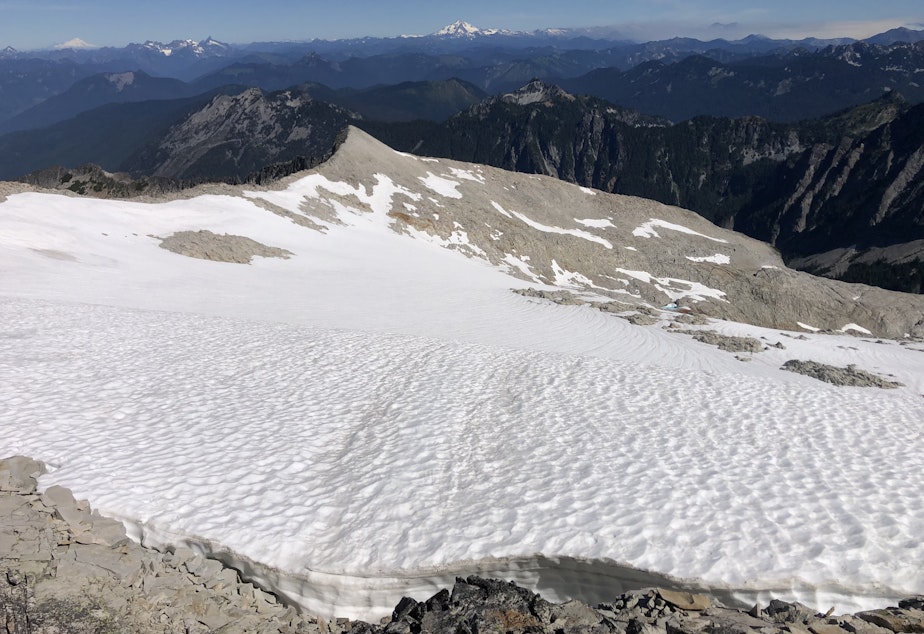caption: The Foss Glacier, Mount Hinman’s sole remaining glacier, with Mount Baker, Glacier Peak, and wildfire smoke on the horizon on Aug. 14, 2022.