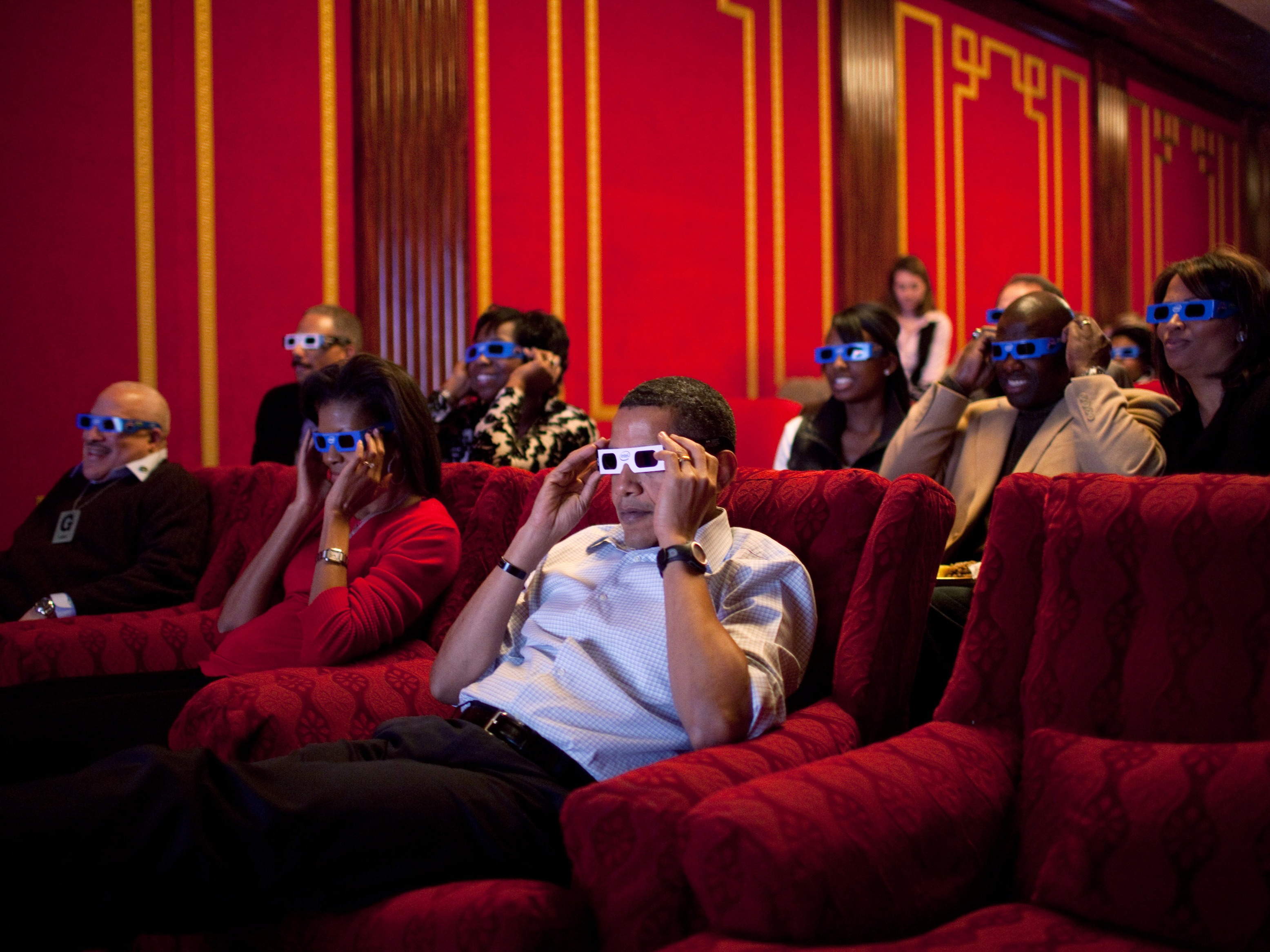 caption: Former President Barack Obama and first lady Michelle Obama wear 3-D glasses during a Super Bowl party in the White House Family Theater in 2009.