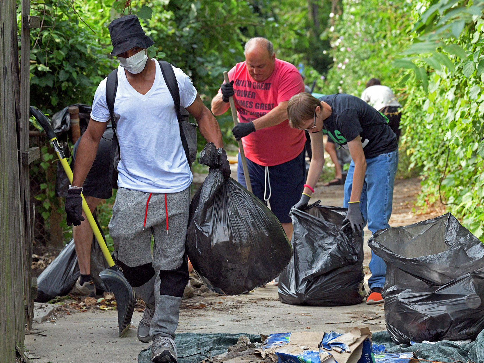 caption: Volunteers clear an alley strewn with trash near Fulton Avenue in Baltimore, Md., on Aug. 5. Another group was in the city Thursday doing similar clean up.