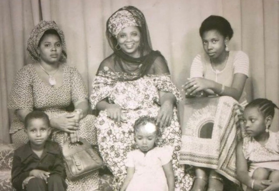 caption: Family portrait taken in Niger in 1978. Leila M’baye's great-grandma, Hadjia Mecca, smiles in the center of the top row. Hadjia's two daughters sit on either side of her, and her three grandchildren sit in the front row. Leila’s mom, Aissata M’baye, is on the lower right.