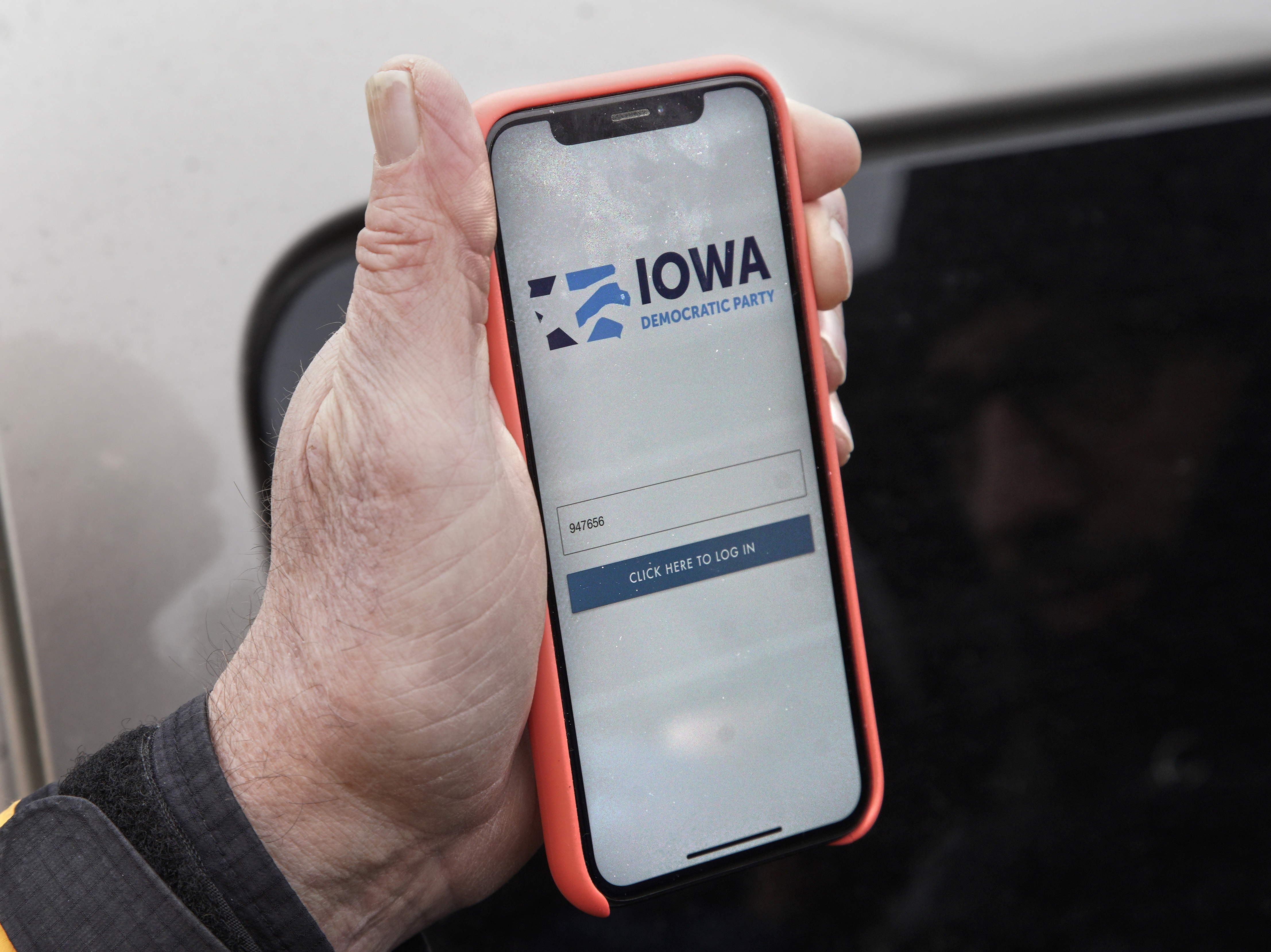 caption: Precinct captain Carl Voss of Des Moines displays the Iowa Democratic Party caucus reporting app on his phone outside the Iowa Democratic Party headquarters on Tuesday.