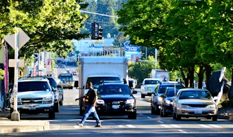 caption: A pedestrian crosses Lake City Way near Northeast 125th Street in Seattle.