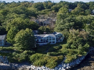 caption: This image provided by Vinal Applebee shows the home of Lisa Gorman in the foreground, the poisoned oak trees behind her home, and the home of the alleged perpetrators behind the dead trees, in Camden, Maine.