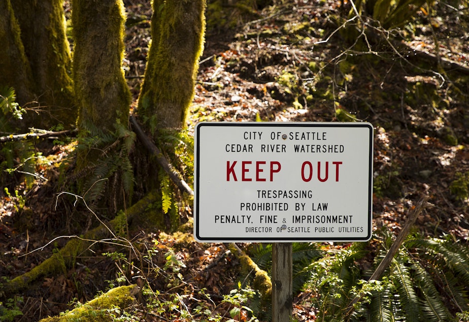 caption: A sign instructs people to keep out  of the protected swath of forest that hides the watershed area on Friday, April 29, 2022, at the Cedar River Watershed Education Center in North Bend. 
