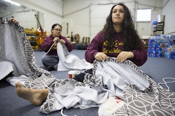 caption: Leilani Kaaiwela-Pedreira, center, and Jessica Whalen, left, assemble their traditional Kahiko dresses on Thursday, March 22, 2018, at the halau in Federal Way. 