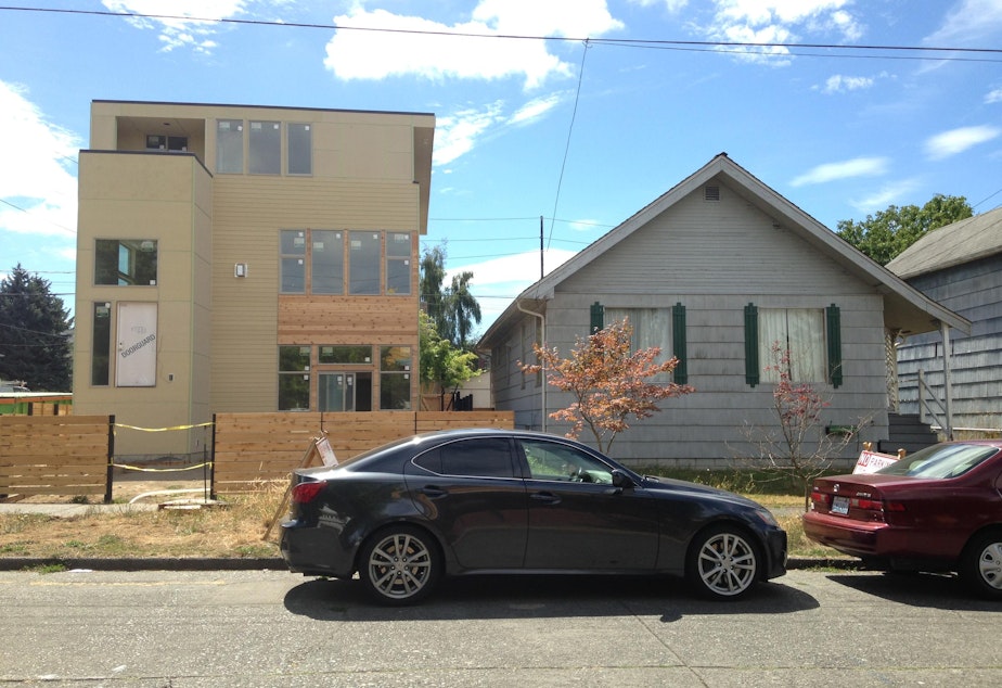 caption: A new, larger house goes up alongside an older home in Seattle.