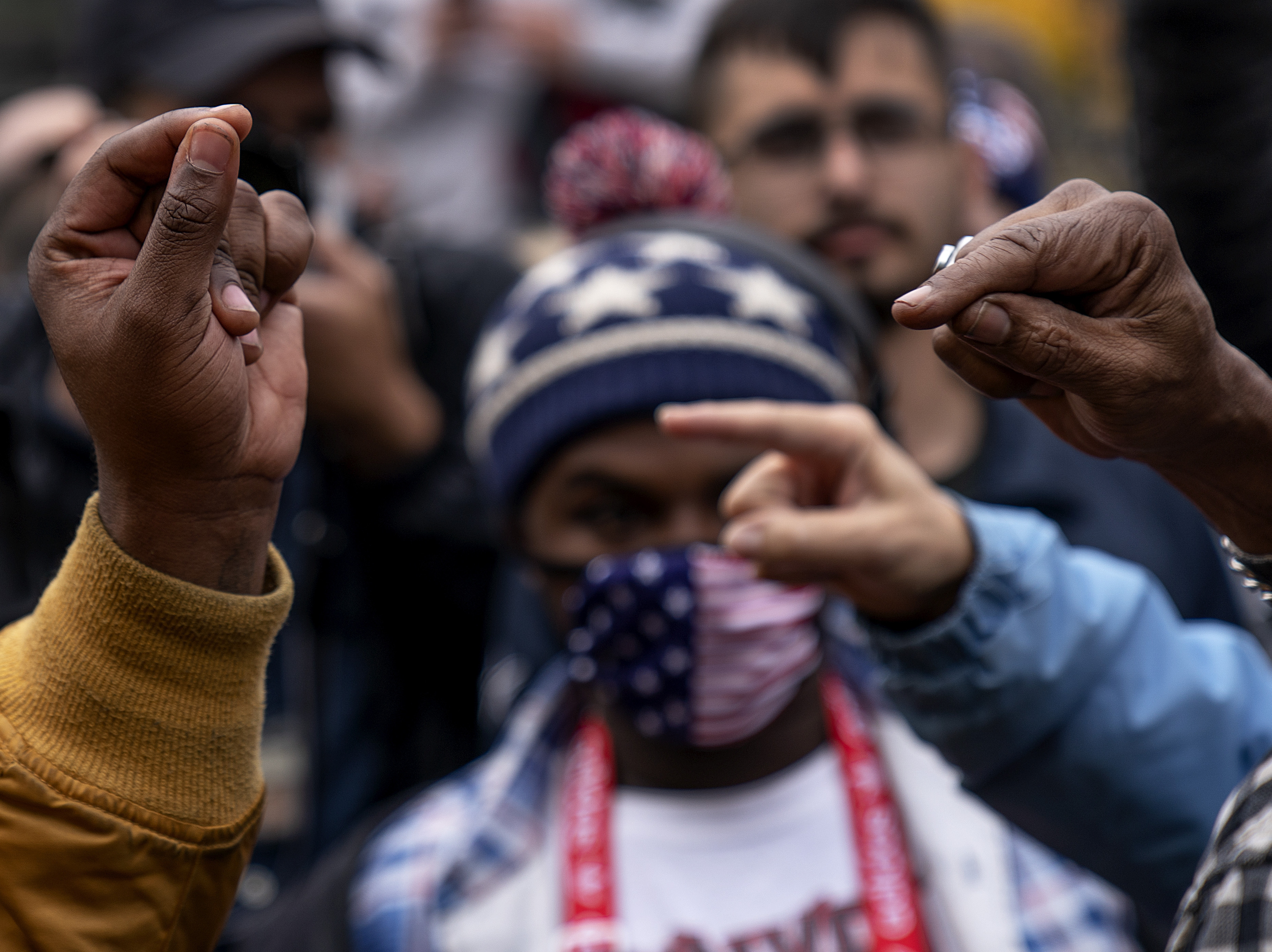 caption: The hands of Biden supporter Angelo Austin, and Trump supporter C.L. Bryant, right, gesture as they argue while Trump supporters demonstrate against the election results in Detroit on Nov. 5, 2020.