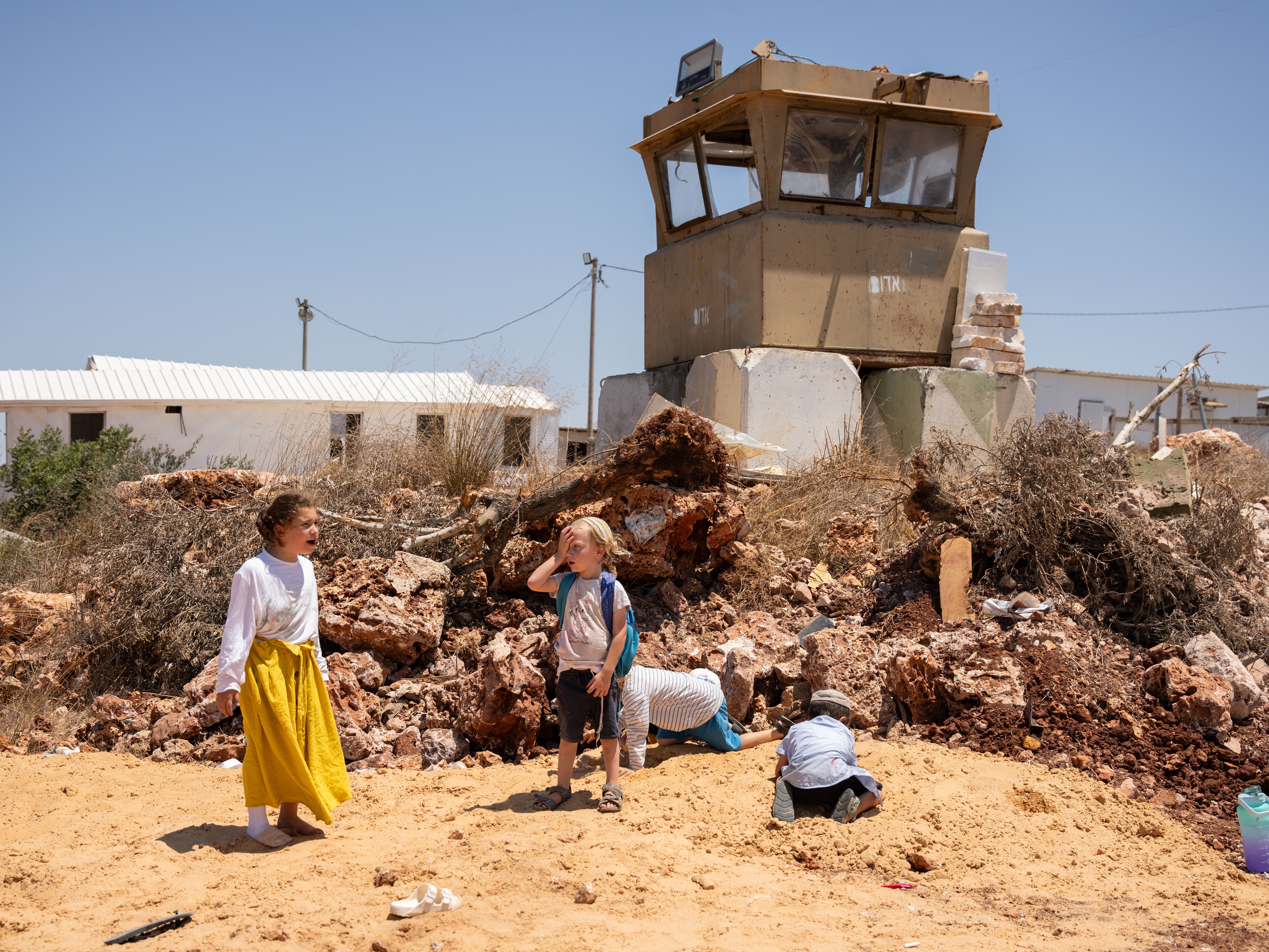 caption: Children play by a guard tower in the Jewish settlement of Evyatar in the West Bank on July 18. The current Israeli government, which is strongly supportive of settlements, recently authorized Evyatar and four other outposts that did not previously have government approval.