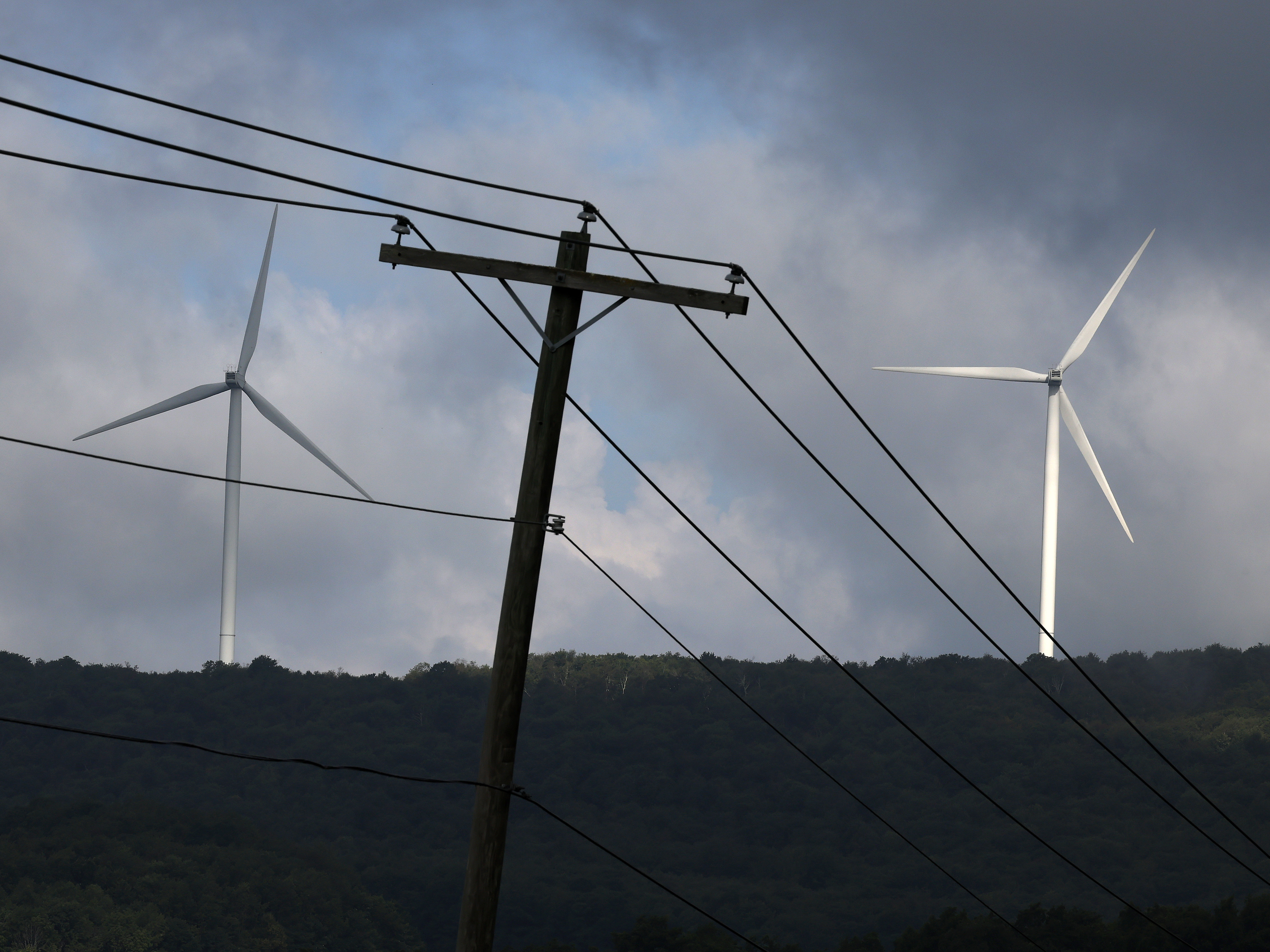 caption: Turbines from the Roth Rock wind farm spin on the spine of Backbone Mountain near Oakland, Md., on August 23. The International Energy Agency says renewable energy projects are getting a boost of investment from governments around the world.